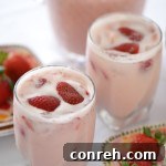 Agua de Fresa, a refreshing strawberry drink garnished with fresh berries.