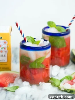 A glass of Watermelon Chamomile Iced Tea with Basil, garnished with fresh basil and watermelon chunks.