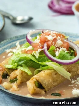 Crispy Potato Tacos Dorados on a bed of pinto bean puree, topped with fresh vegetables and cheese.