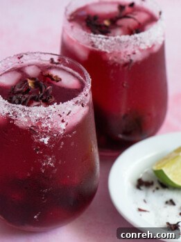 Hibiscus Cosmopolitan cocktail in a martini glass with lime garnish.