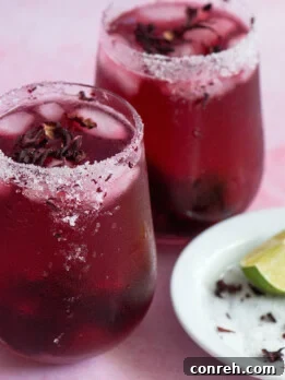 Hibiscus Rhapsody 2 Vibrant Hibiscus Cosmopolitan cocktail garnished with a lime wedge