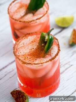 A vibrant Russian Vampire cocktail in a chili-rimmed glass, garnished with a jalapeño slice.