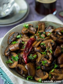 A close-up shot of freshly cooked garlic fried mushrooms garnished with cilantro in a rustic bowl.
