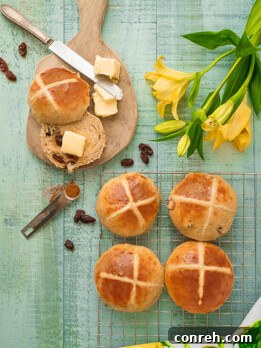 Beautifully baked Hot Cross Buns with white icing crosses on a wire rack.