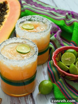 A vibrant glass of Papaya and Ginger Agua Fresca, garnished with fresh lime and mint, on a summery background.