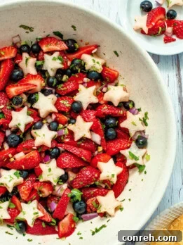 Vibrant Red, White, and Blue Salsa with crisp jicama, juicy strawberries, and plump blueberries, served with tortilla chips for a festive appetizer.
