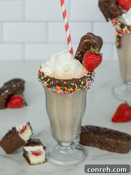 A deliciously creamy Gansito Milkshake, topped with whipped cream, chocolate sprinkles, and a fresh strawberry, capturing the essence of the classic Mexican snack cake.
