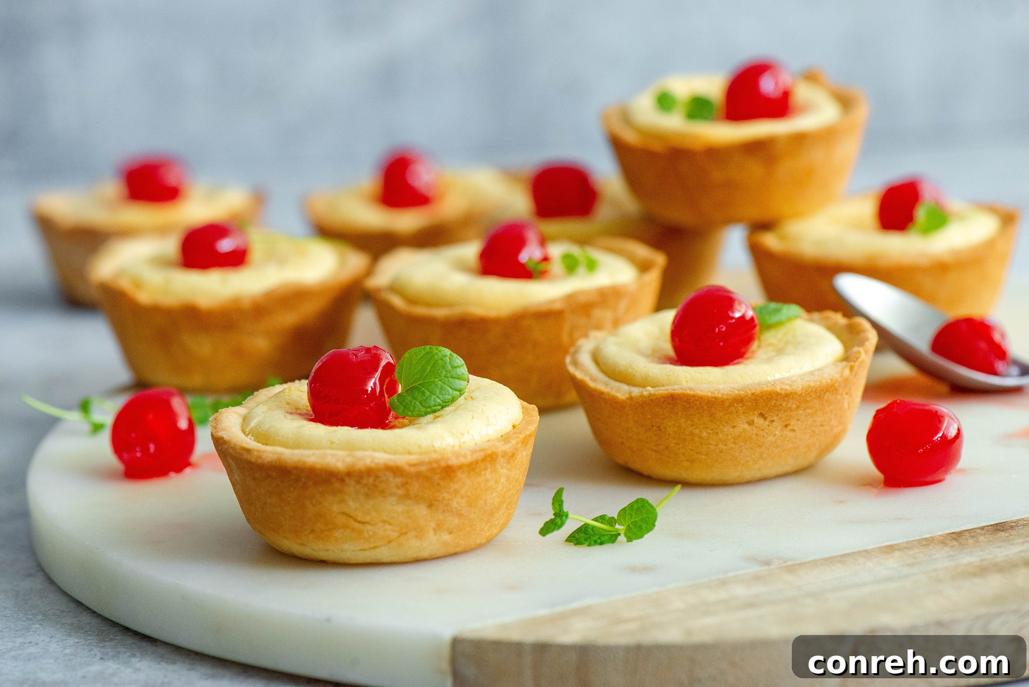 Close-up of freshly baked Cubiletes de Queso topped with a cherry, ready to be enjoyed.
