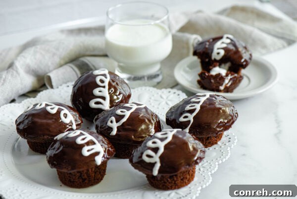 Close-up of a homemade chocolate cupcake with white creamy filling visible and a perfect chocolate ganache swirl.