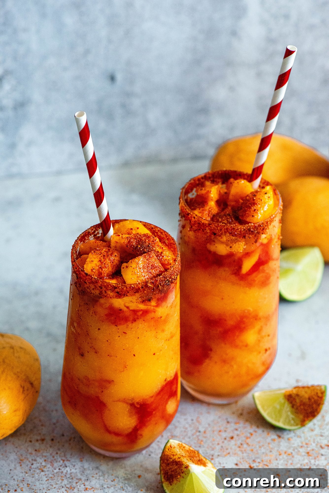 A vibrant Mangonada drink, a sweet, spicy, and tangy Mexican frozen mango treat, garnished with fresh mango chunks and a tamarind straw.
