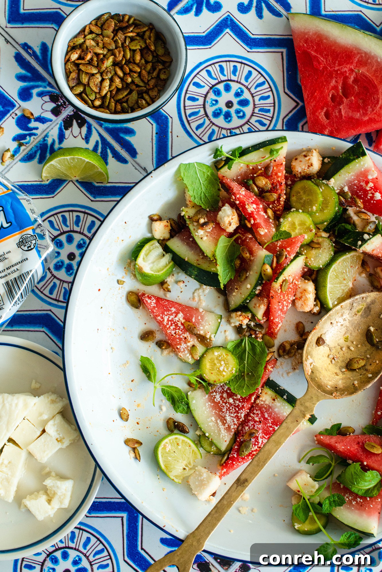 Assortment of fresh ingredients including watermelon, cucumber, mint, and cheeses for the salad