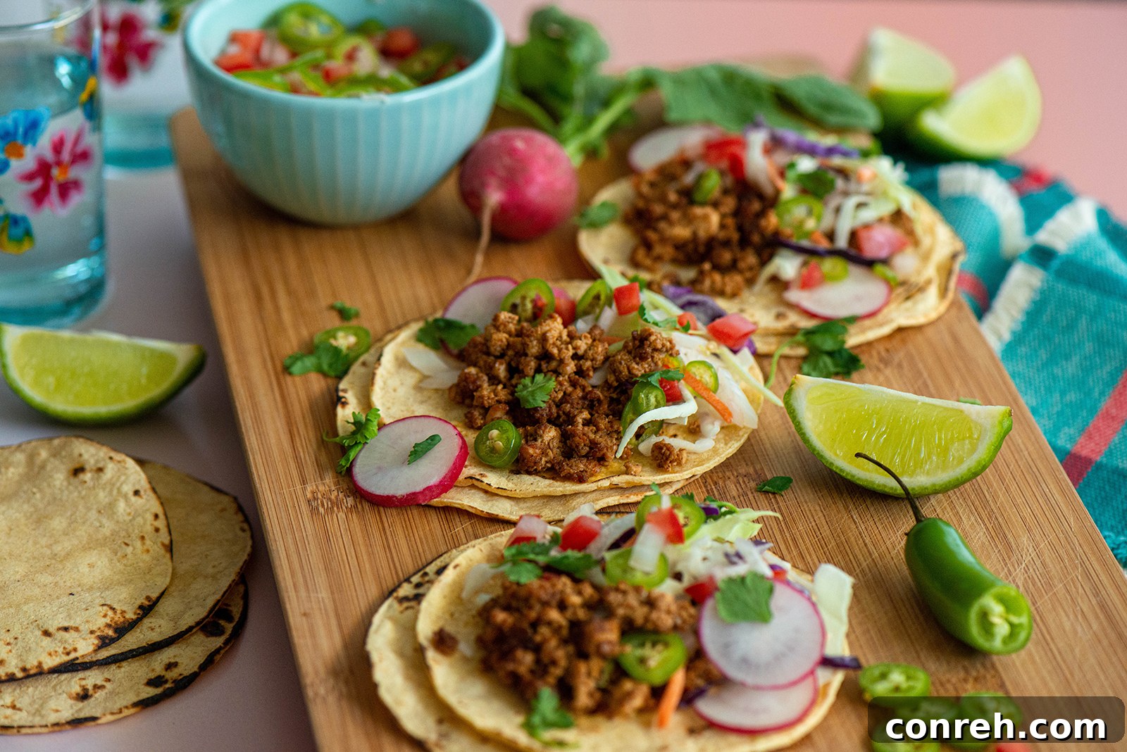 Close-up of a hand holding a tofu street taco, showcasing the colorful toppings.