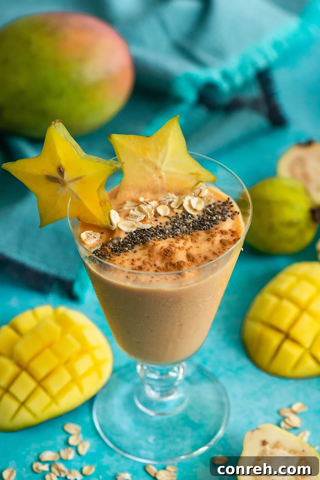 A refreshing Mango Guava Smoothie in a tall glass, garnished with a vibrant star fruit slice, set against a bright, airy background.
