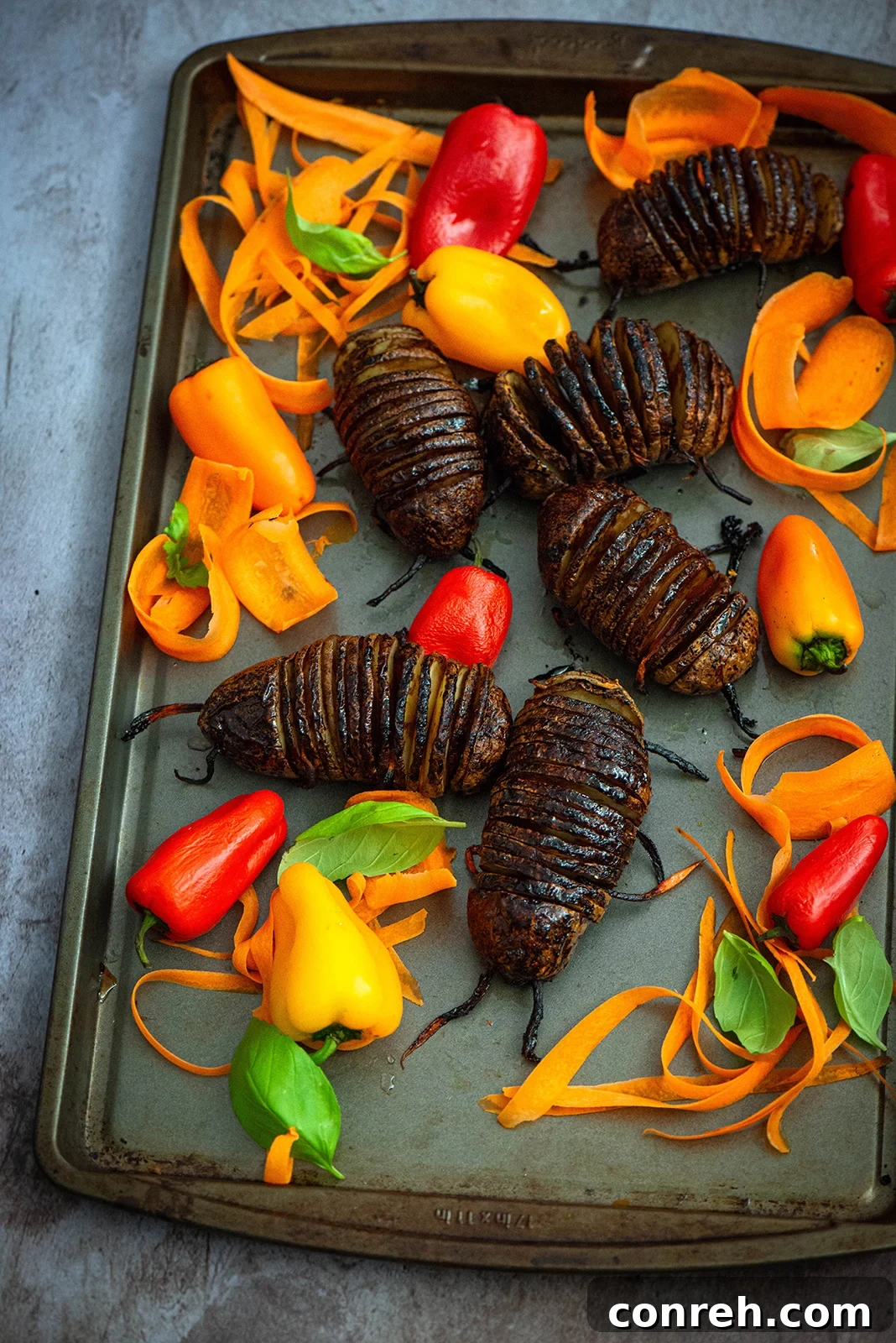 A serving tray filled with Hasselback potato bugs and assorted raw vegetables, ready for a Halloween party.