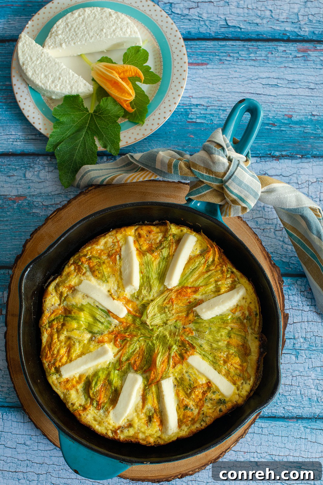 Close-up shot of the frittata showcasing delicate squash blossoms and queso fresco slices arranged on top.