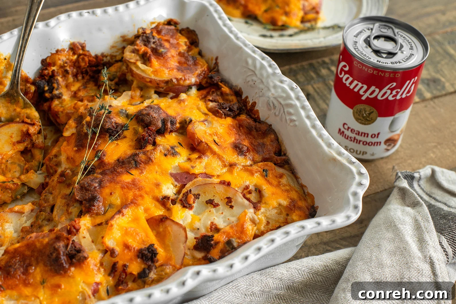 Close-up shot of the golden-brown, bubbling cheesy scalloped potatoes, showcasing the melted cheese and a hint of the chorizo peeking through the layers.