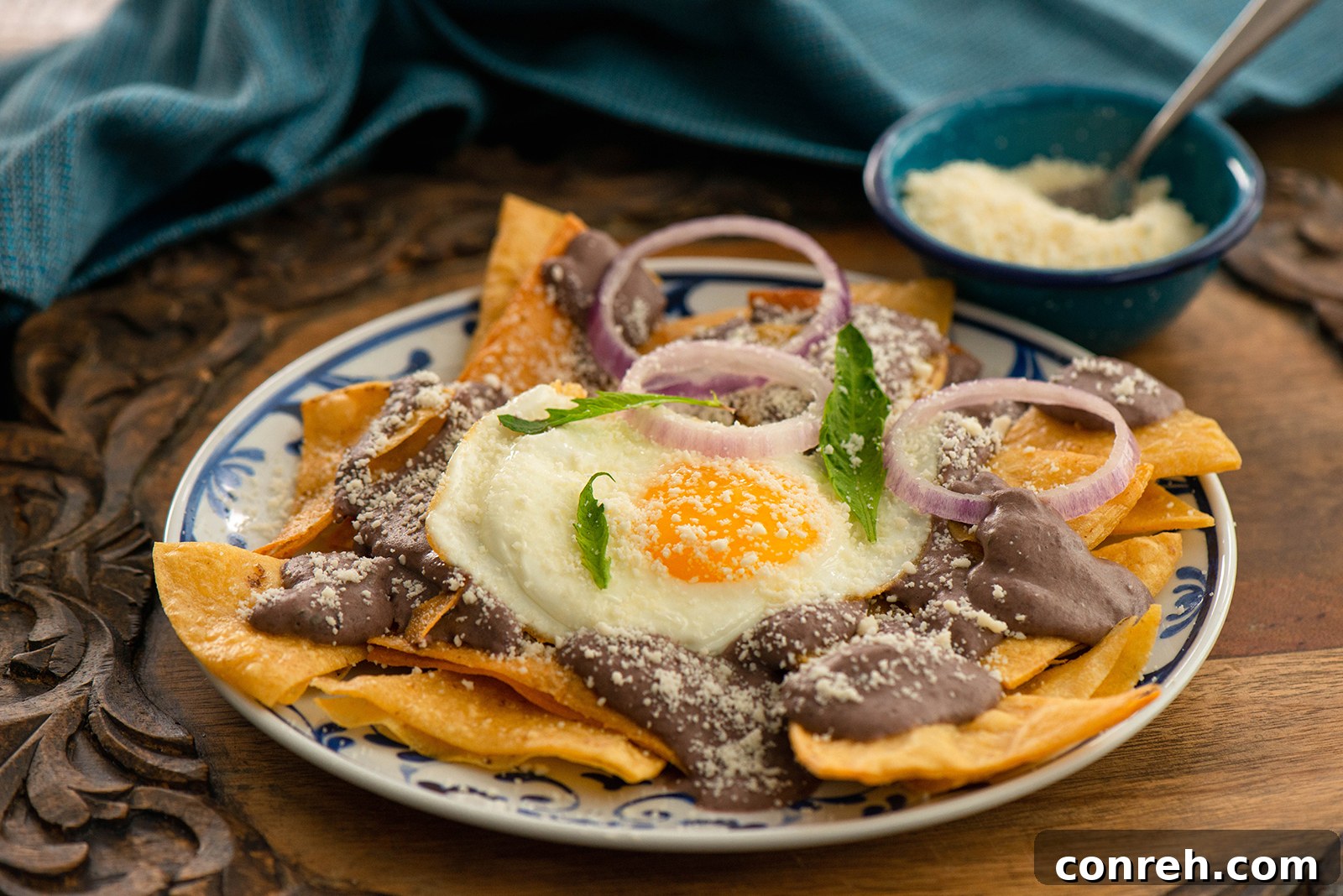 A close-up of a plate of Black Bean Chilaquiles, highlighting the texture of the tortillas and the rich bean sauce.