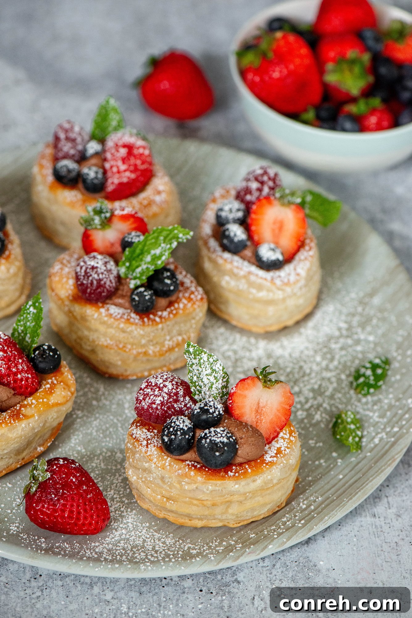 Flaky puff pastry volovanes filled with rich chocolate cream and topped with fresh berries and powdered sugar.