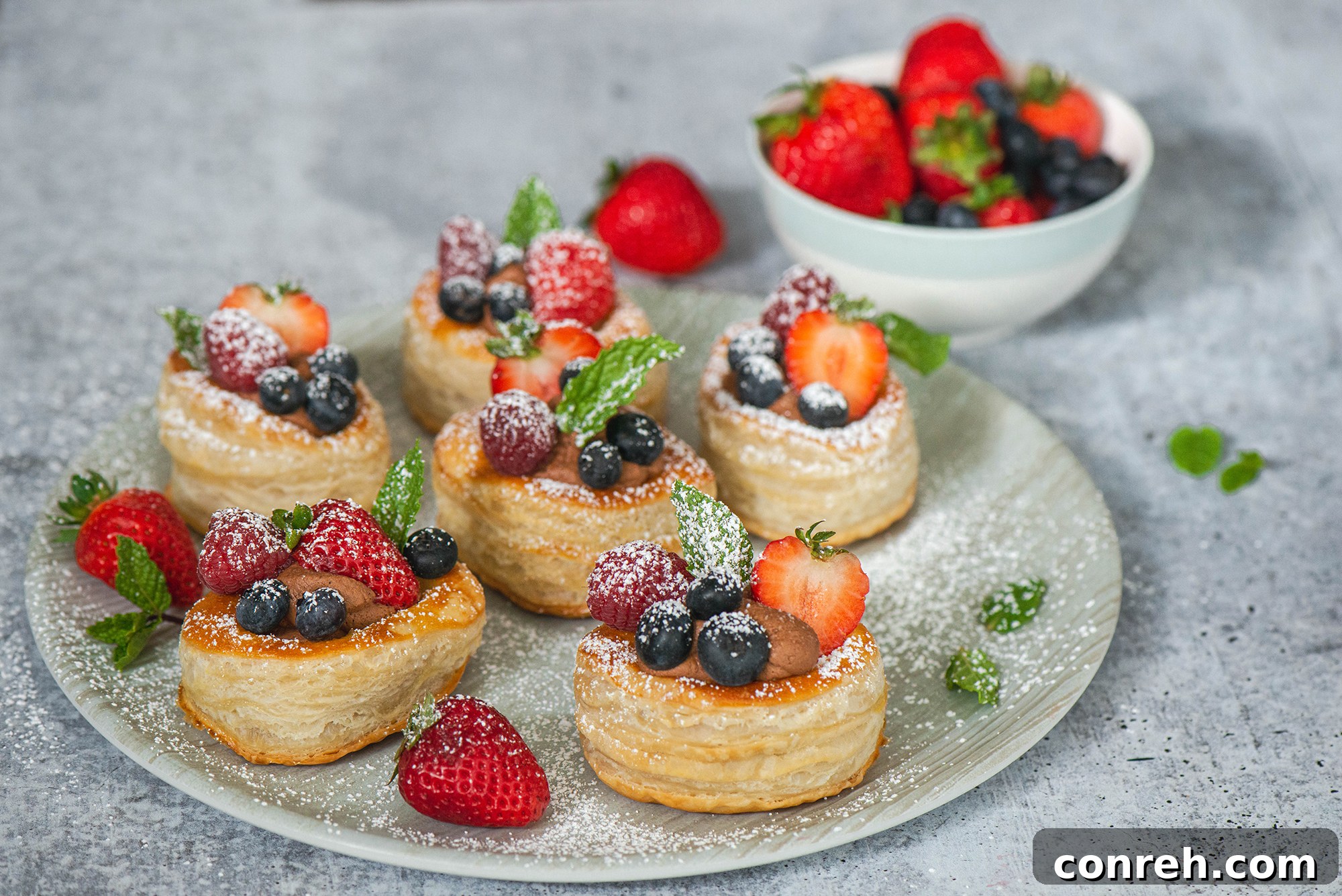 Arrangement of chocolate cream volovanes on a serving platter with extra berries.