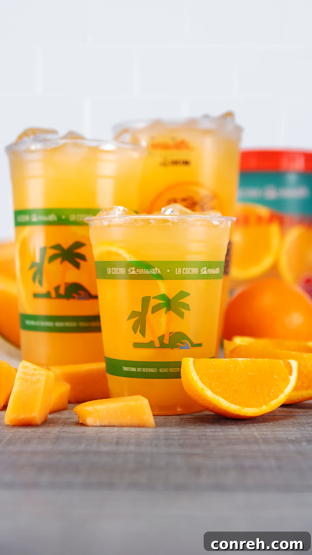 A vibrant glass of Cantaloupe and Orange Agua Fresca, garnished with fresh fruit, on a bright summer day.
