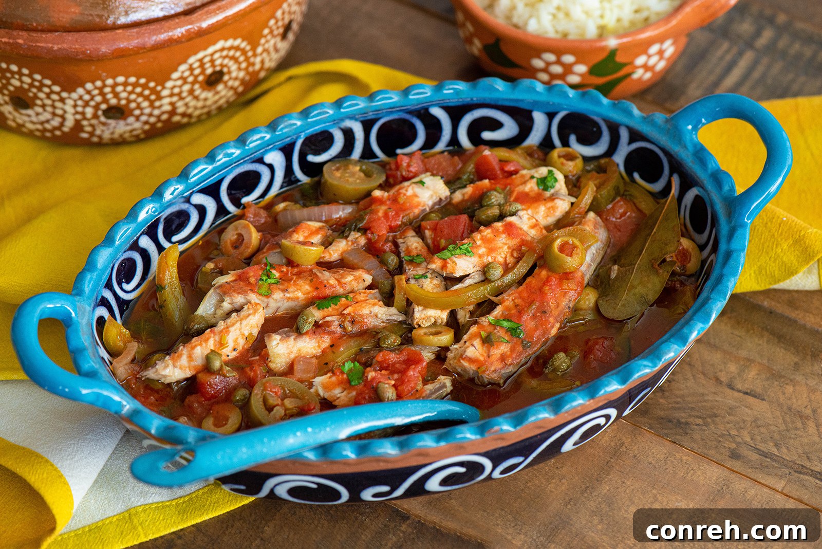 Close-up of Veracruz Style Mackerel in a pan with olives and bell peppers