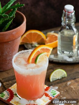 A close-up of a Paloma cocktail, showing the sugar rim, ice, and grapefruit slice.