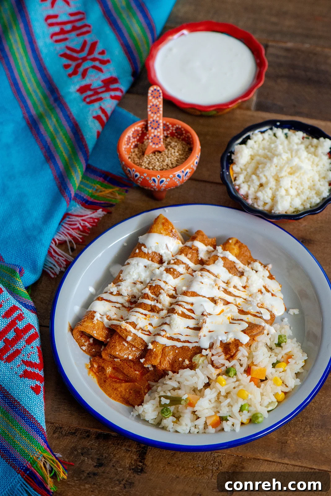 A vibrant plate of Sesame Enchiladas with Queso Fresco and Crema Mexicana, garnished with cilantro.