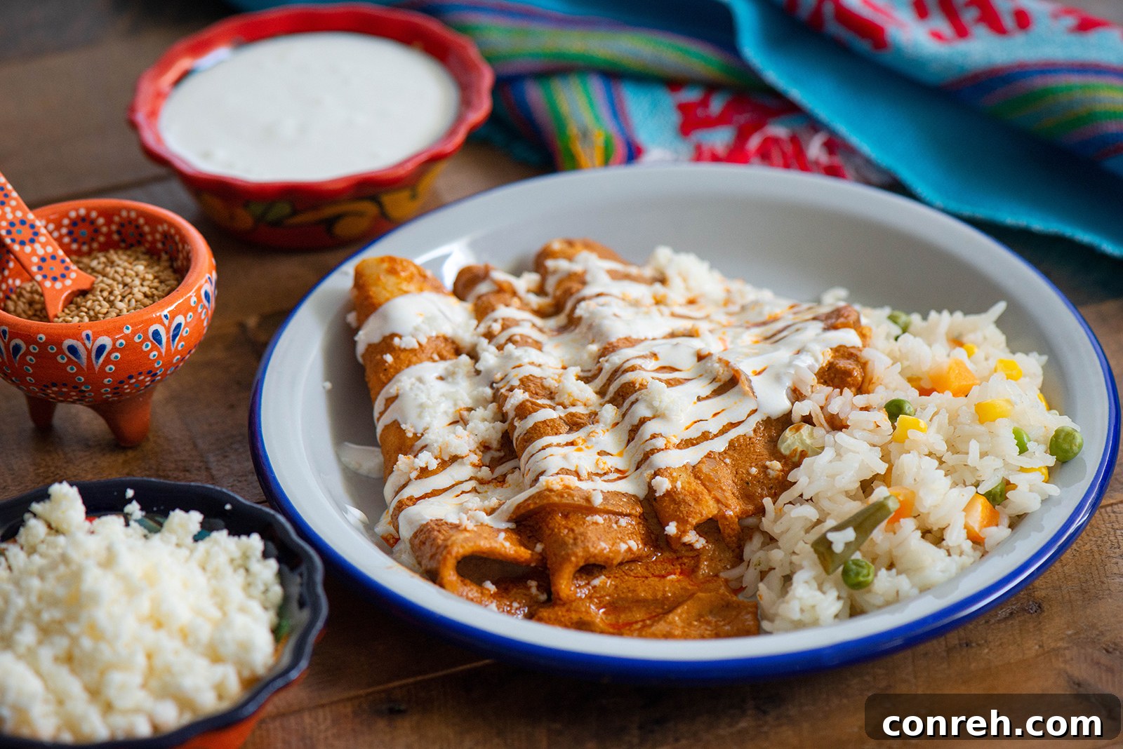 Close-up of freshly prepared enchiladas, showing the sauce, crema, and queso fresco.