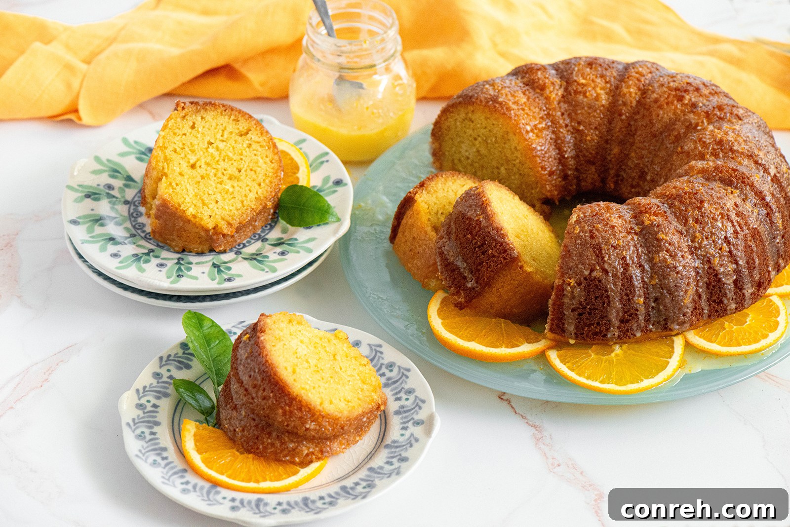 A slice of orange cake with glaze and fresh orange on a white plate.