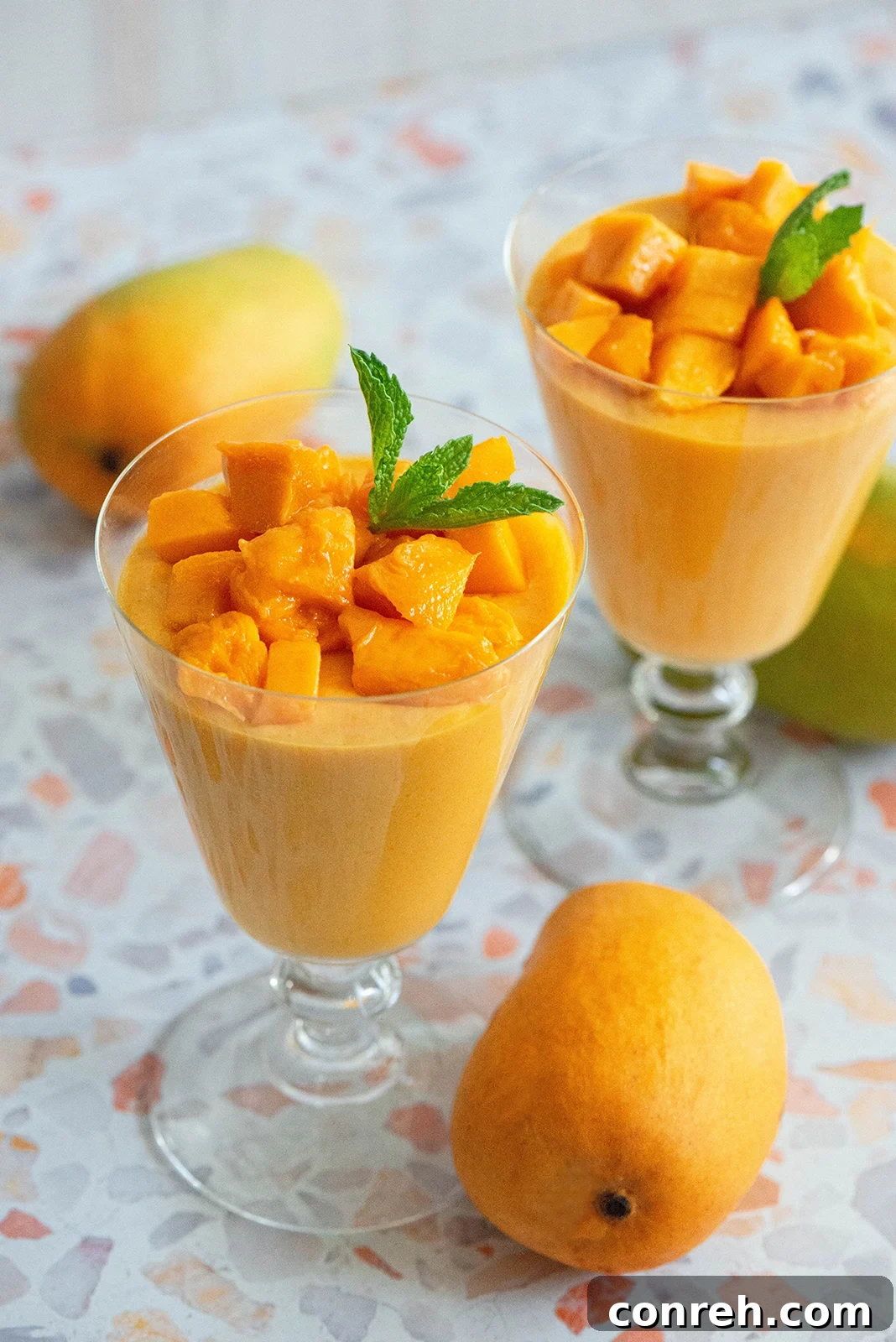 Vibrant mango mousse served in elegant glasses, garnished with fresh mint.