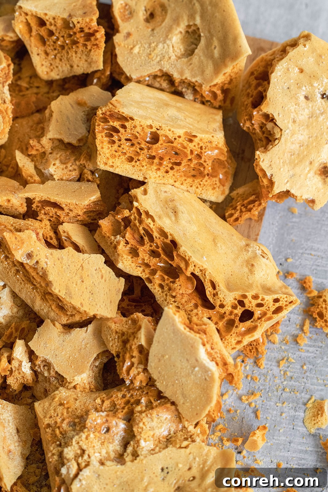 A close-up shot of golden-brown honeycomb candy pieces, showcasing their airy, porous texture.