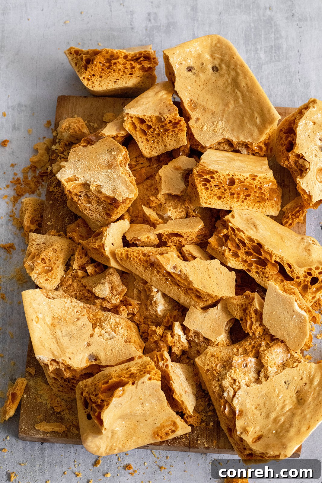 Various pieces of freshly made honeycomb candy scattered on a surface, highlighting their irregular shapes and golden hue.