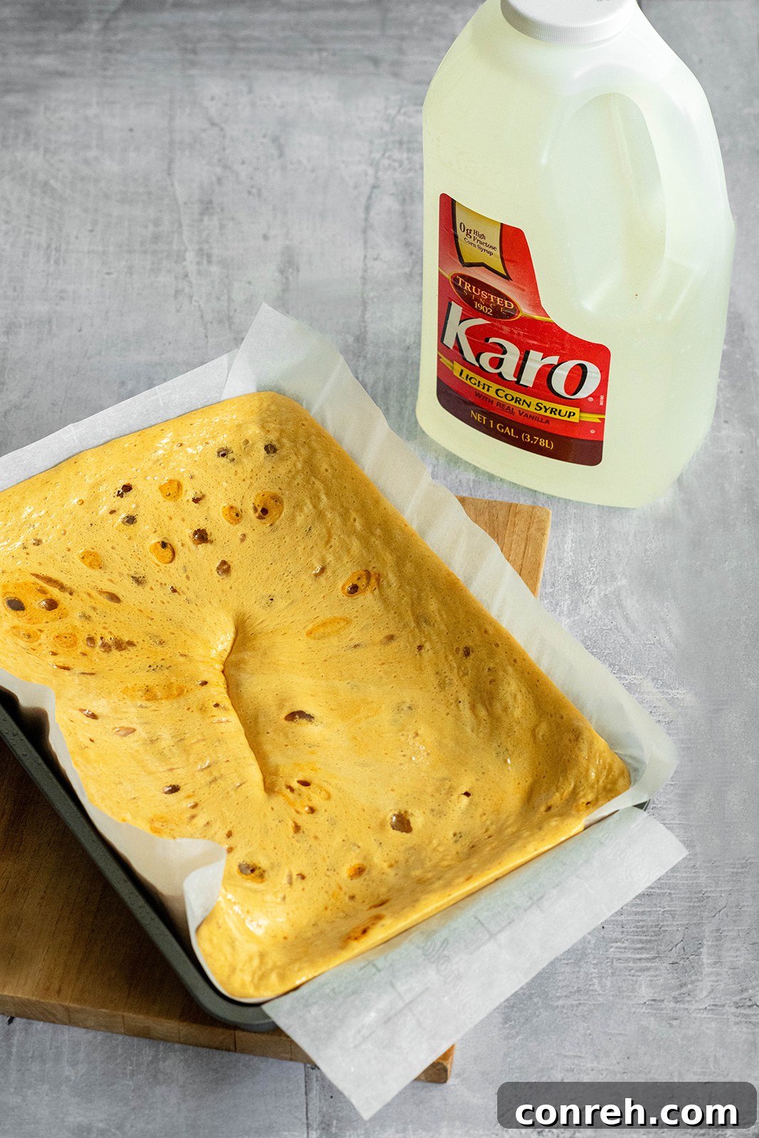A close-up of the honeycomb candy batter rising and foaming in a pan after baking soda has been added.
