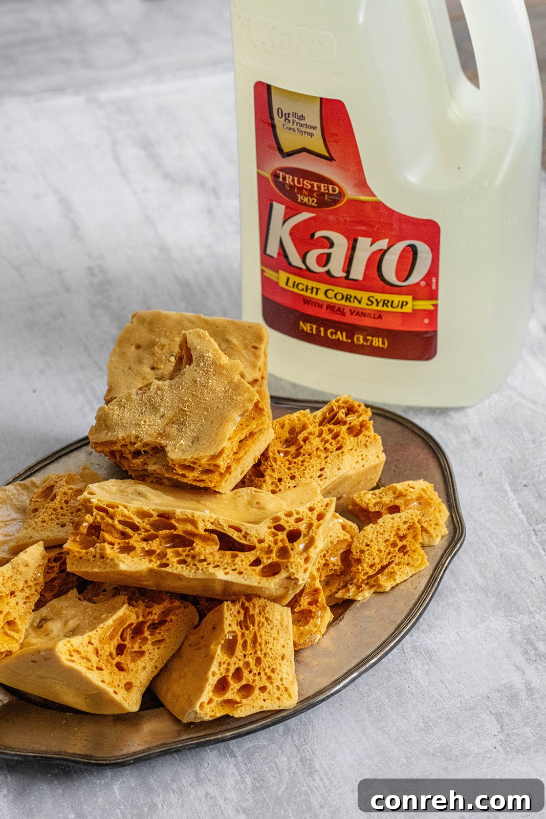 A beautifully arranged plate of homemade honeycomb candy, some pieces plain and some dipped in chocolate.