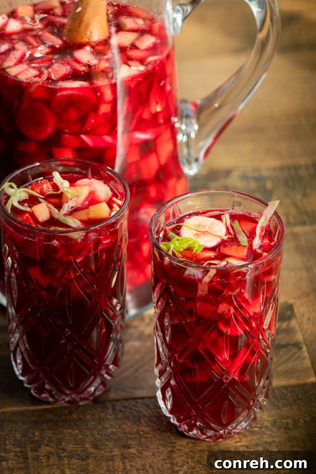 A vibrant glass of Agua de Cuaresma, a traditional Mexican Lenten drink, showcasing its rich red color and fresh fruit pieces.