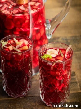 A glass of Agua de Cuaresma, a traditional Mexican Lenten drink, showcasing its rich red color and fresh fruit pieces.