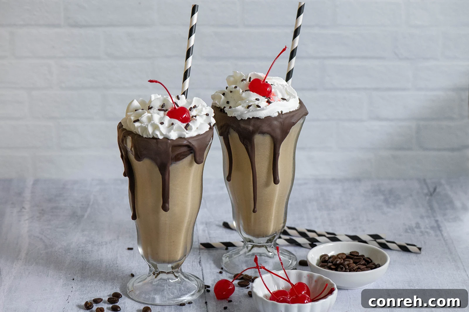 Two glasses of Mexican Coffee Milkshakes, garnished with whipped cream and sprinkles
