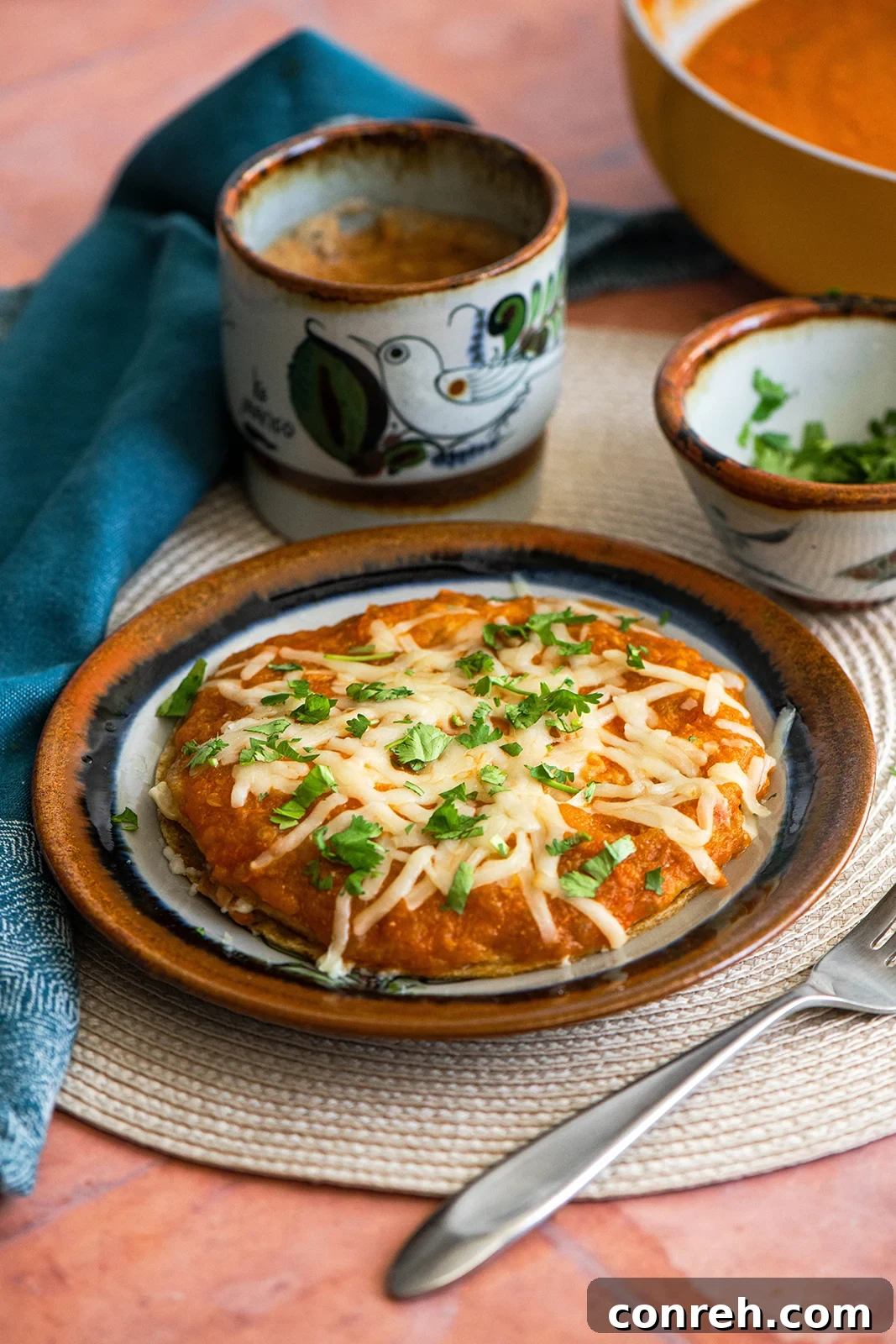Huevos Encobijados, a delicious Mexican breakfast with fried eggs and refried beans between tortillas, covered in spicy tomato sauce.