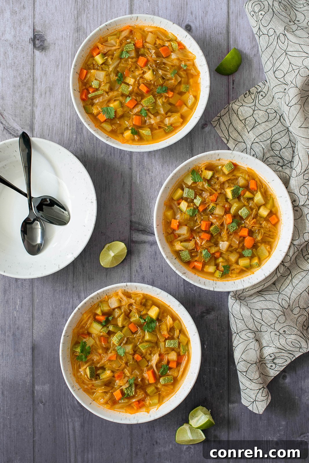 A vibrant bowl of Detox Cabbage Soup, garnished with fresh cilantro and a slice of lime.