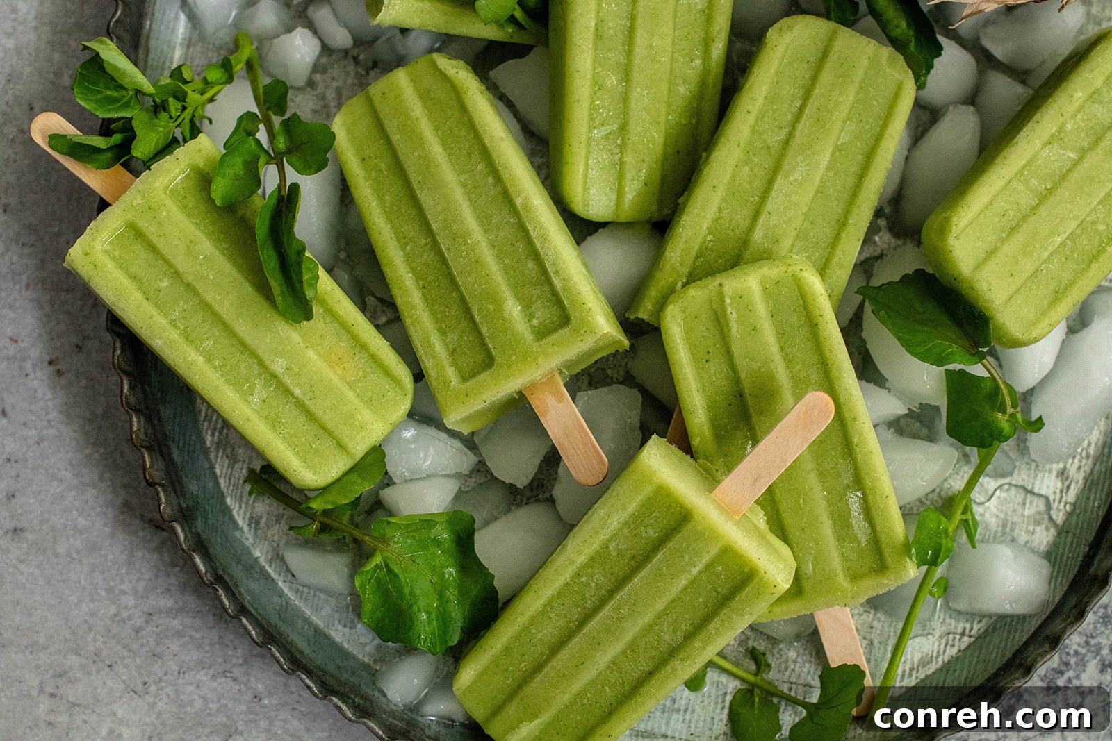 Popsicles in a mold with watercress and fruit