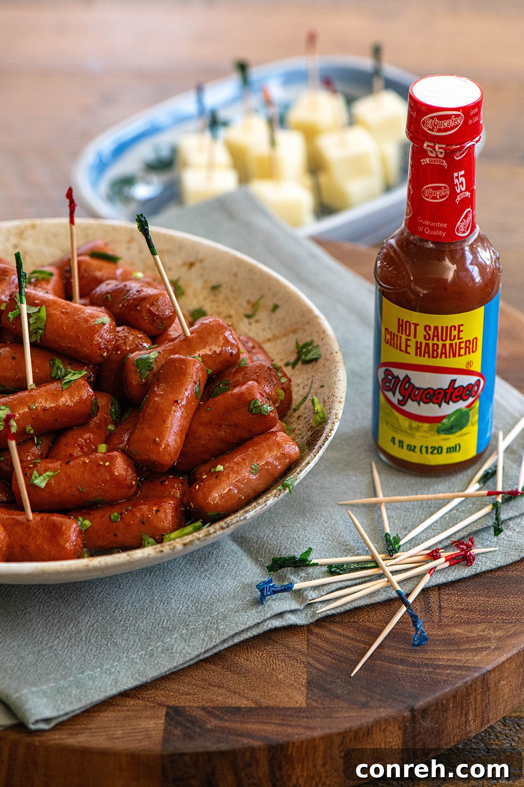 Close-up of Salchichas Botaneras in a bowl with fresh lime and cilantro