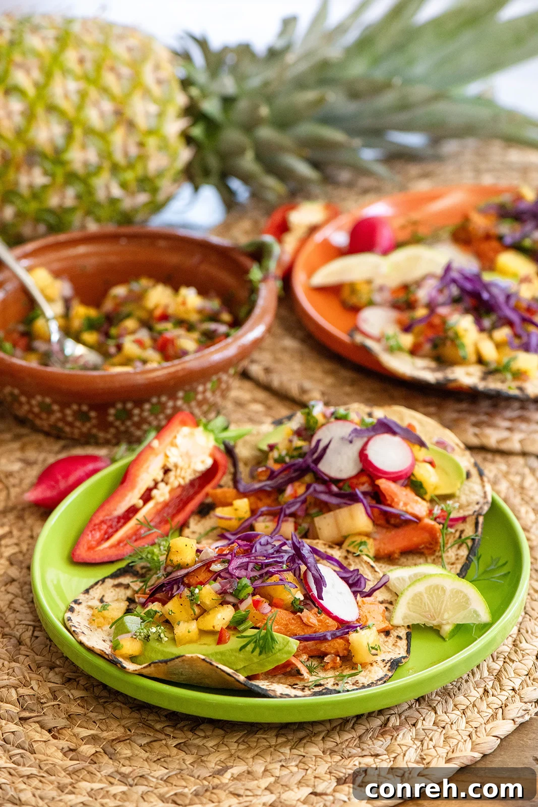 Fresh salmon tacos with vibrant pineapple salsa arranged on corn tortillas, garnished with avocado and purple cabbage, ready to serve.