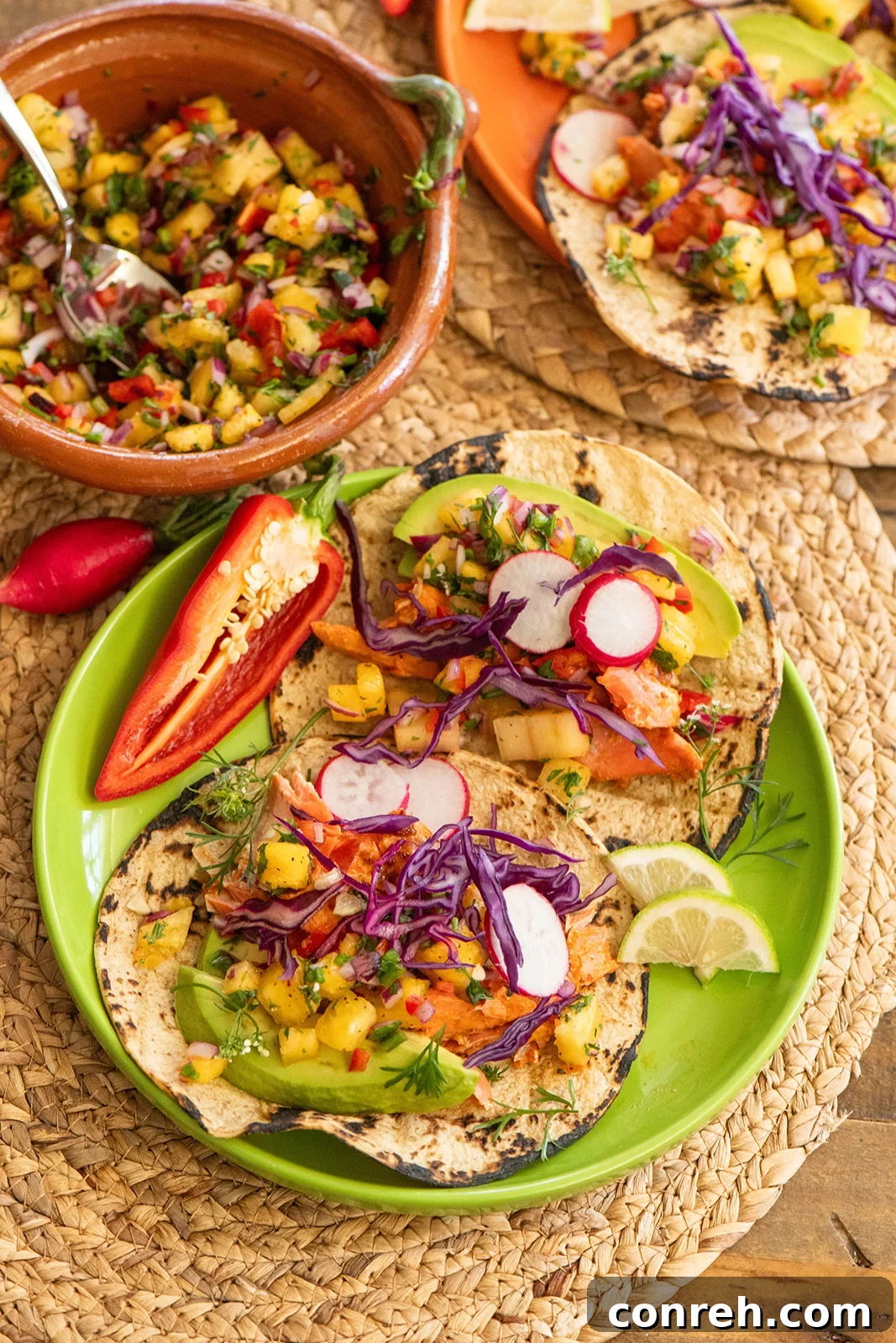 Close-up of a salmon taco with pineapple salsa, avocado, and purple cabbage, showcasing the vibrant colors and textures.