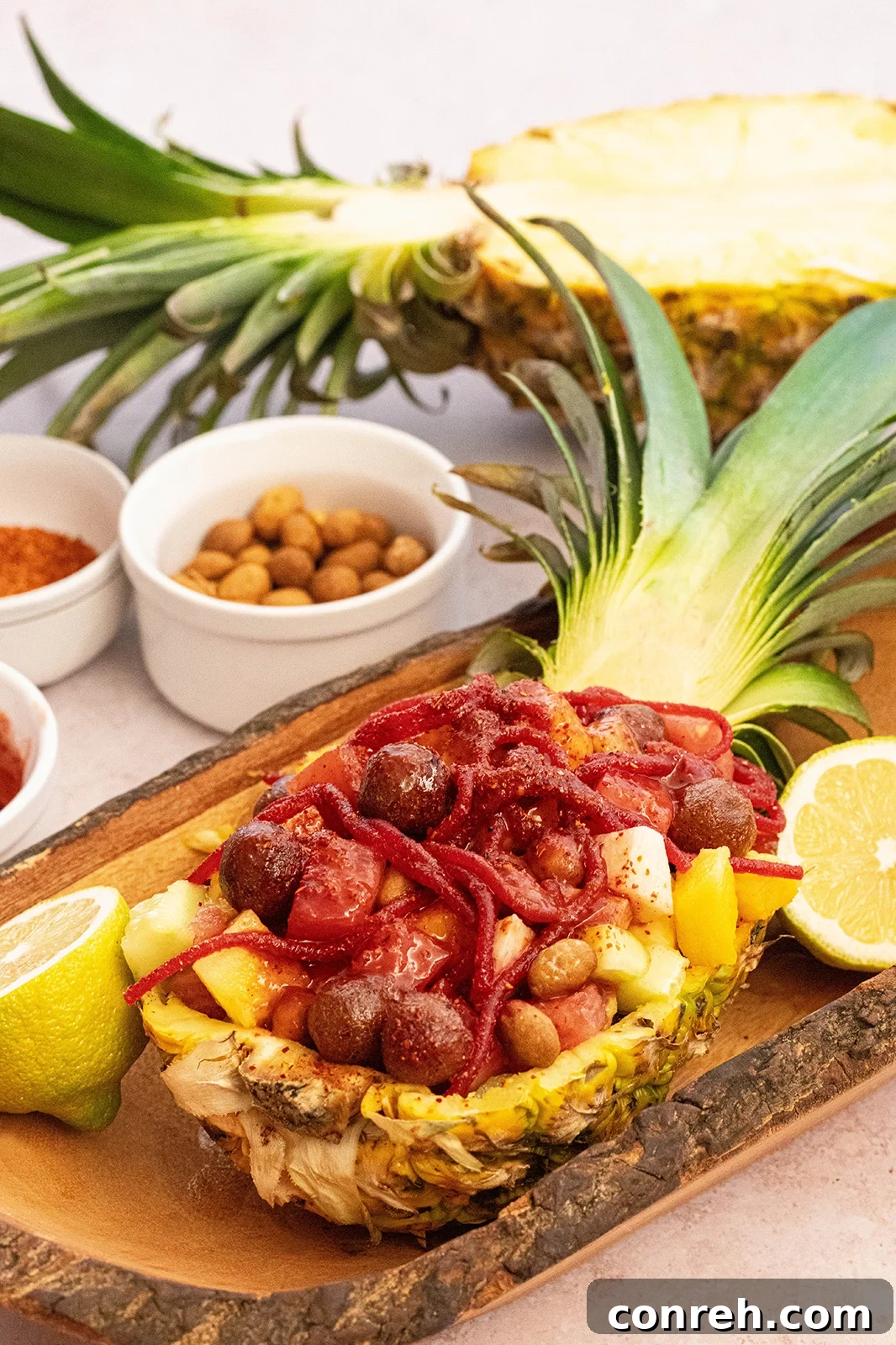 Wild Pineapple 2 Piña Loca served in a halved pineapple, garnished with fresh fruits, peanuts, candies, chamoy, Tajín, and hot sauce.