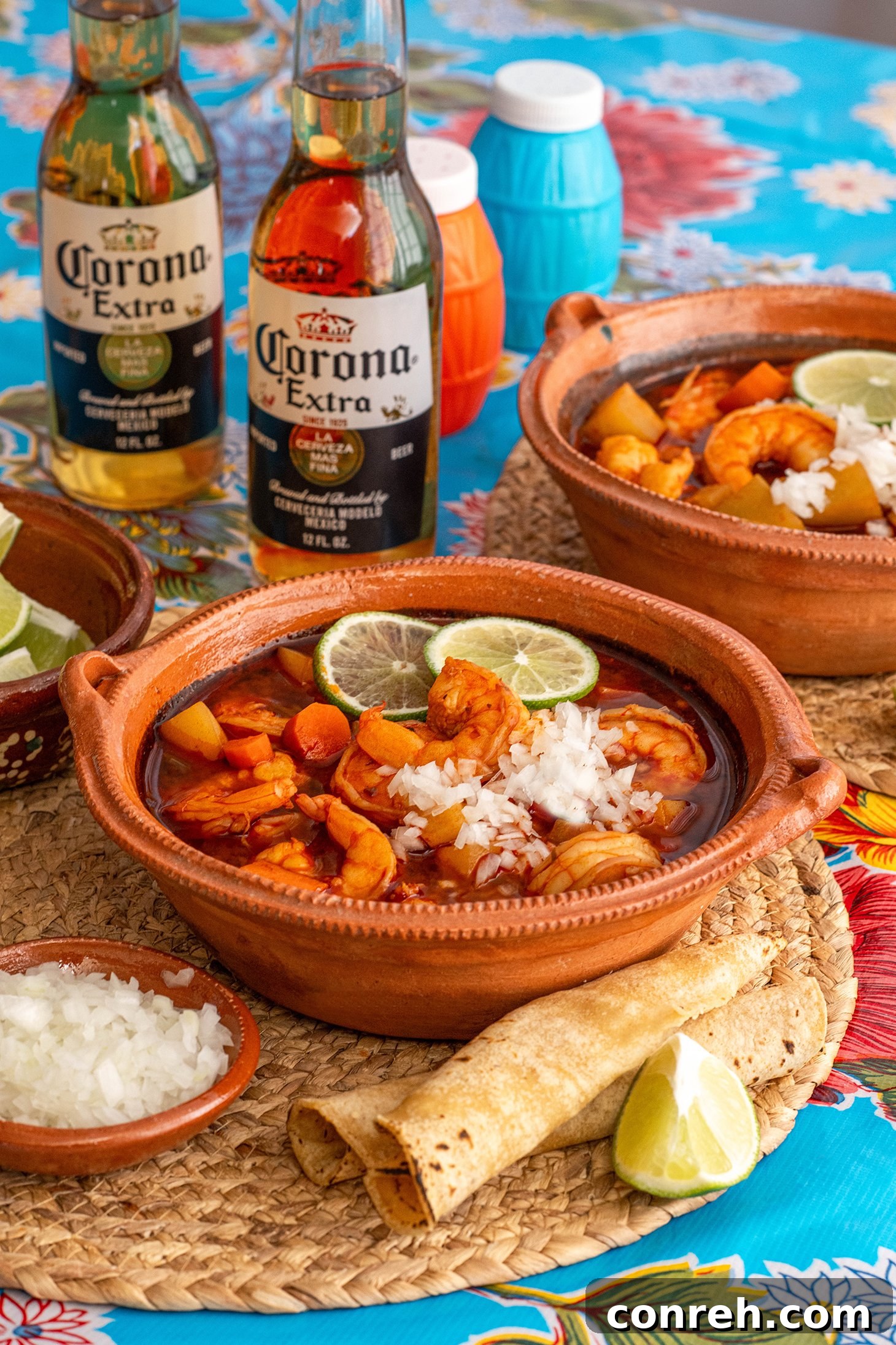 A steaming bowl of vibrant Caldo de Camarón with fresh garnishes.