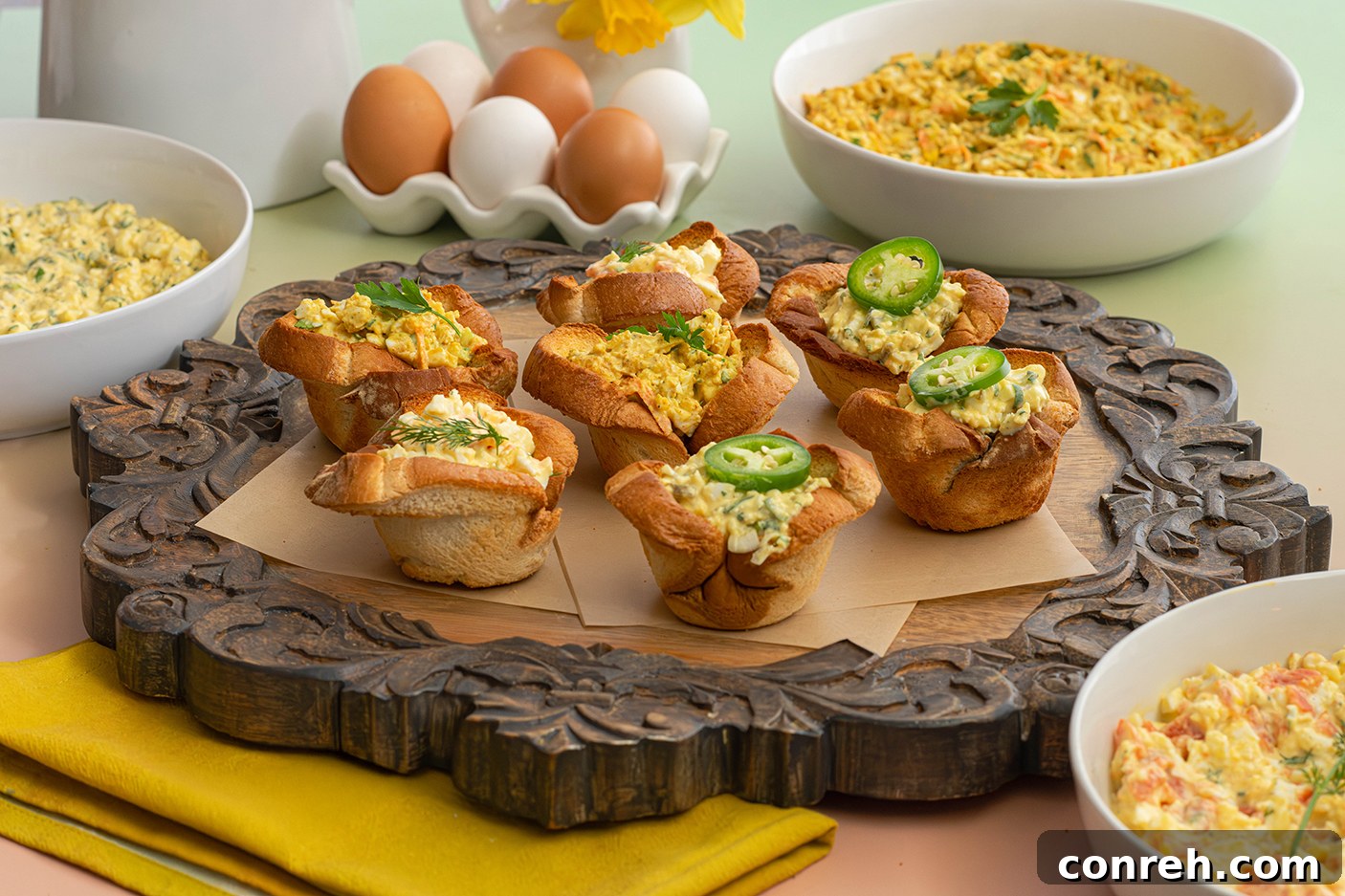 Close-up of a single egg salad bread cup, garnished with herbs.