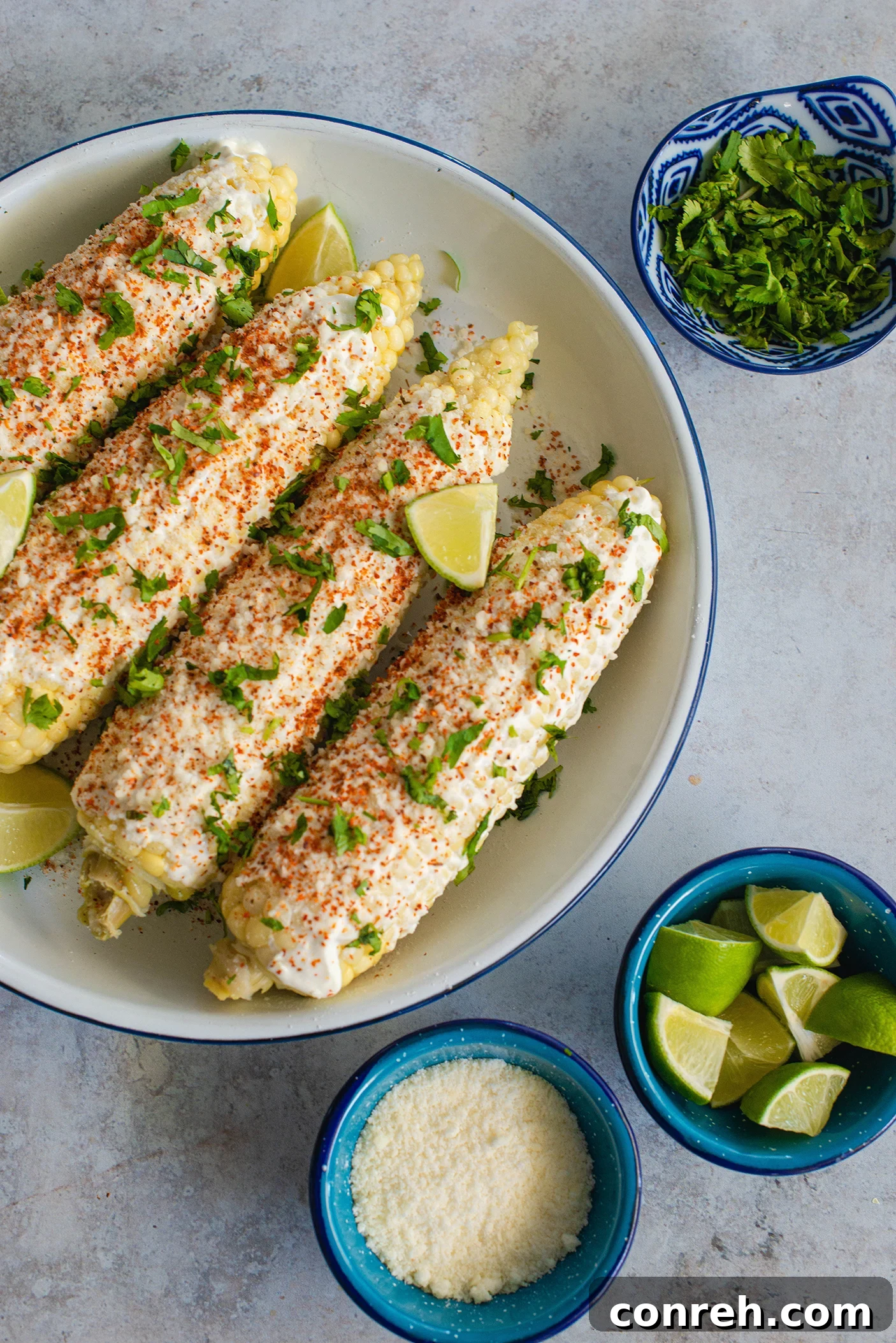 Hand holding a prepared elote with a squeeze of fresh lime.