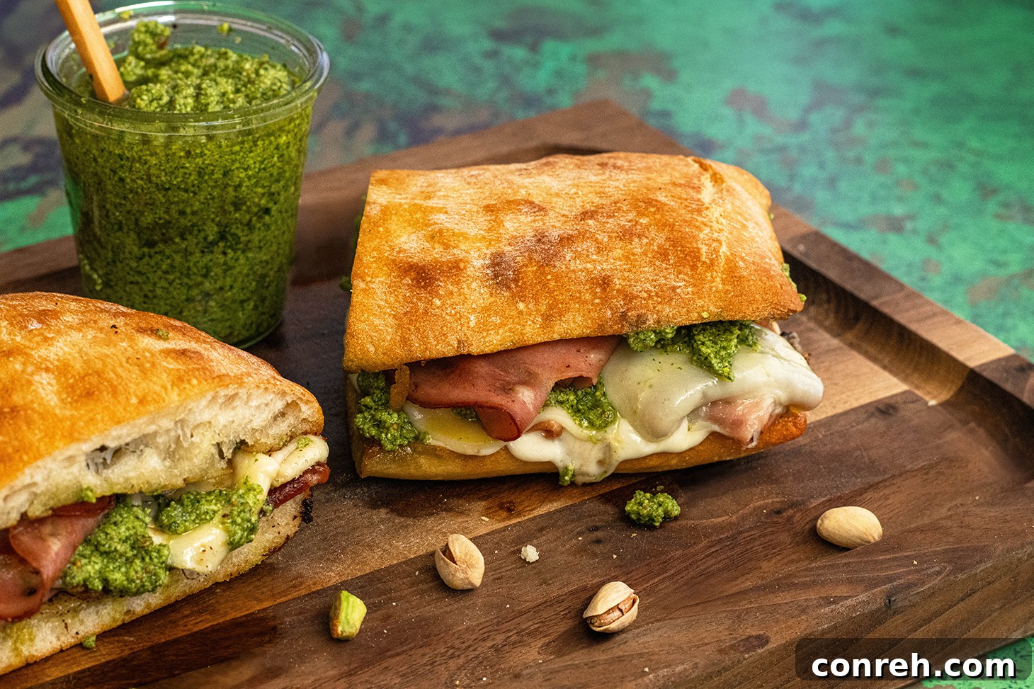 Mortadella Grilled Cheese Sandwich sliced in half, showing melted cheese and green pesto