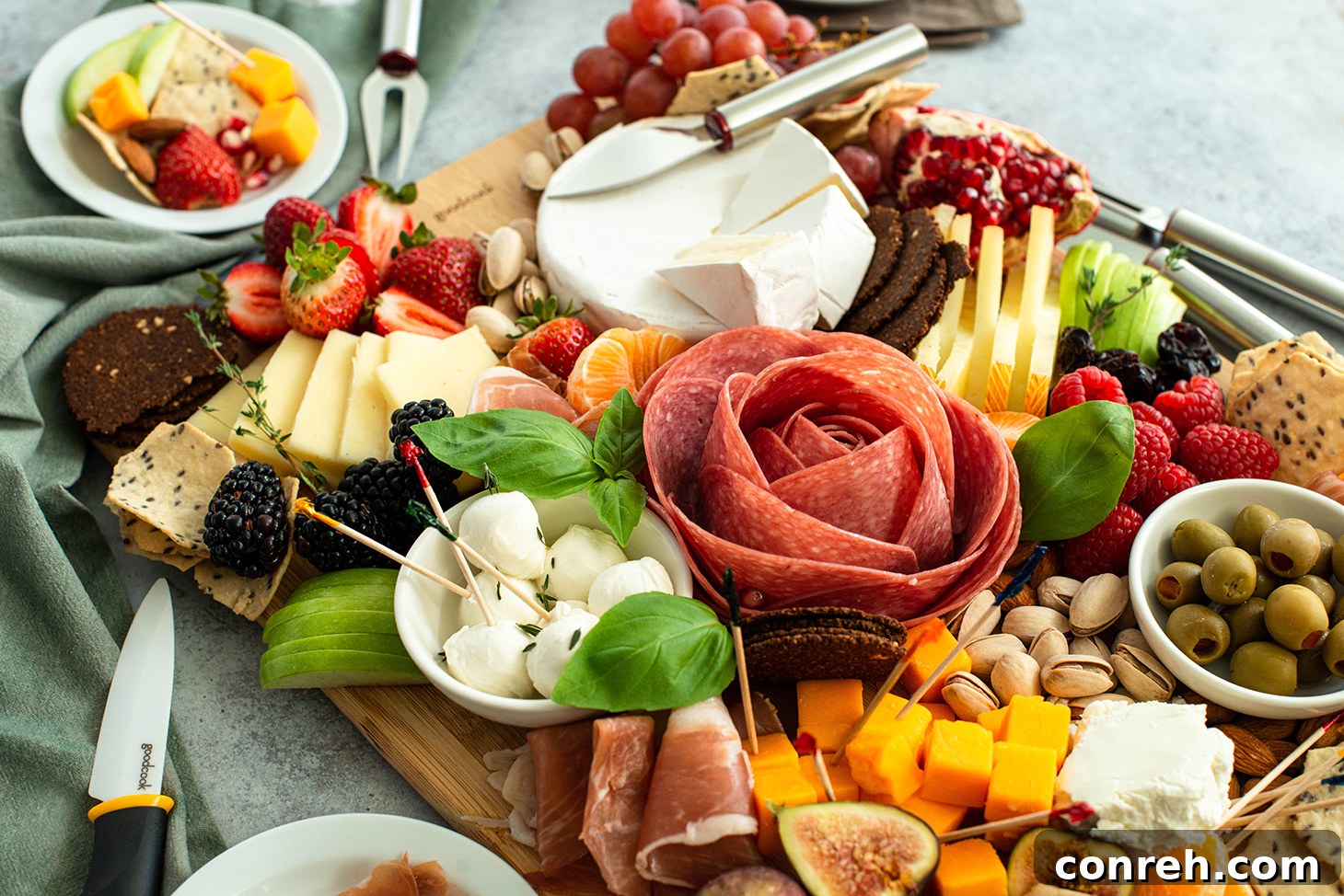 Detailed view of a beautifully crafted salami rose on a charcuterie board with basil leaves