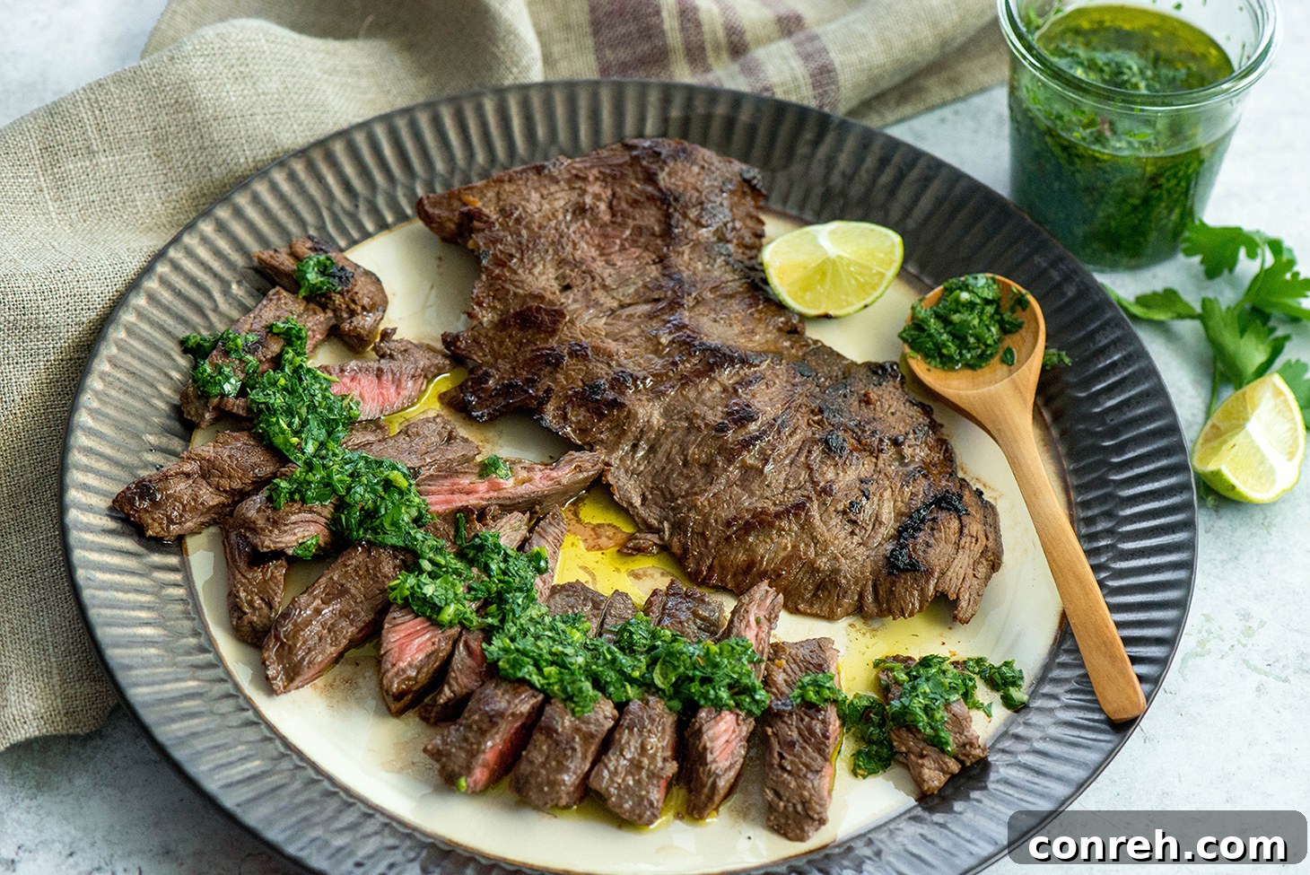 Close-up of perfectly seared churrasco steak, drizzled with fresh chimichurri sauce, garnished with herbs.